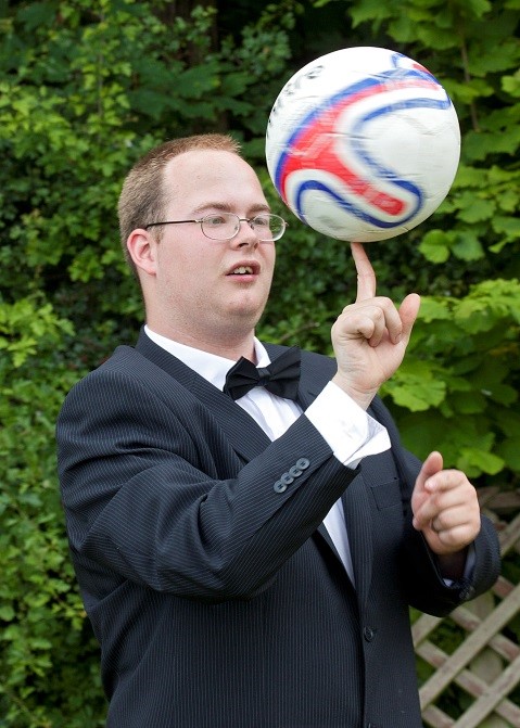 a man in a suit spining a ball on the end of his finger